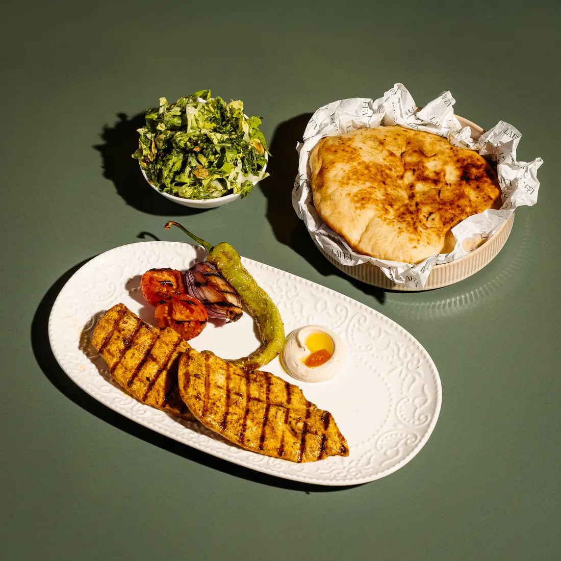 Grilled chicken breast plate with green salad and fresh laffa