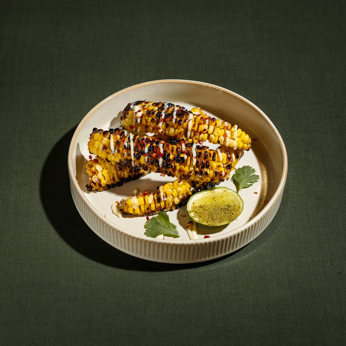 Charred corn ribs with white sauce, chili flakes and lime